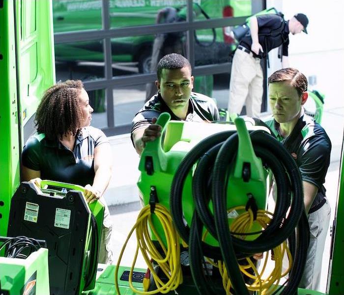 a SERVPRO crew unloading cleaning equipment out of a green van